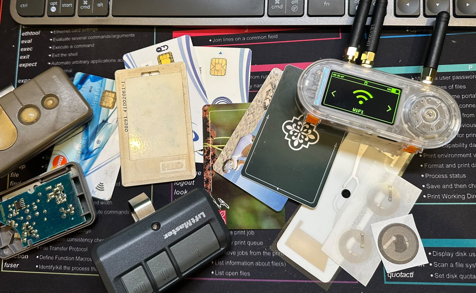 LilyGO T-Embed CC1101 Plus surrounded by remotes, access cards and RFID tags